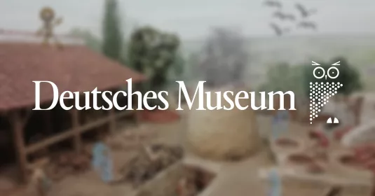 Logo des Deutschen Museums vor einem unscharf gestellten Diorama im Hintergrund